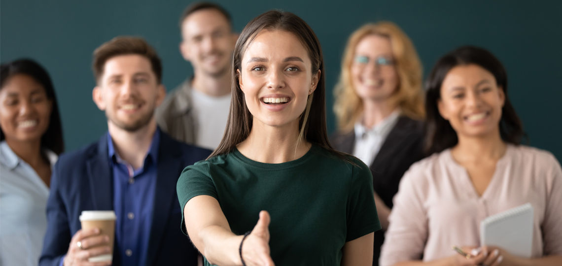 Woman company representative holds out hand for handshake welcoming client